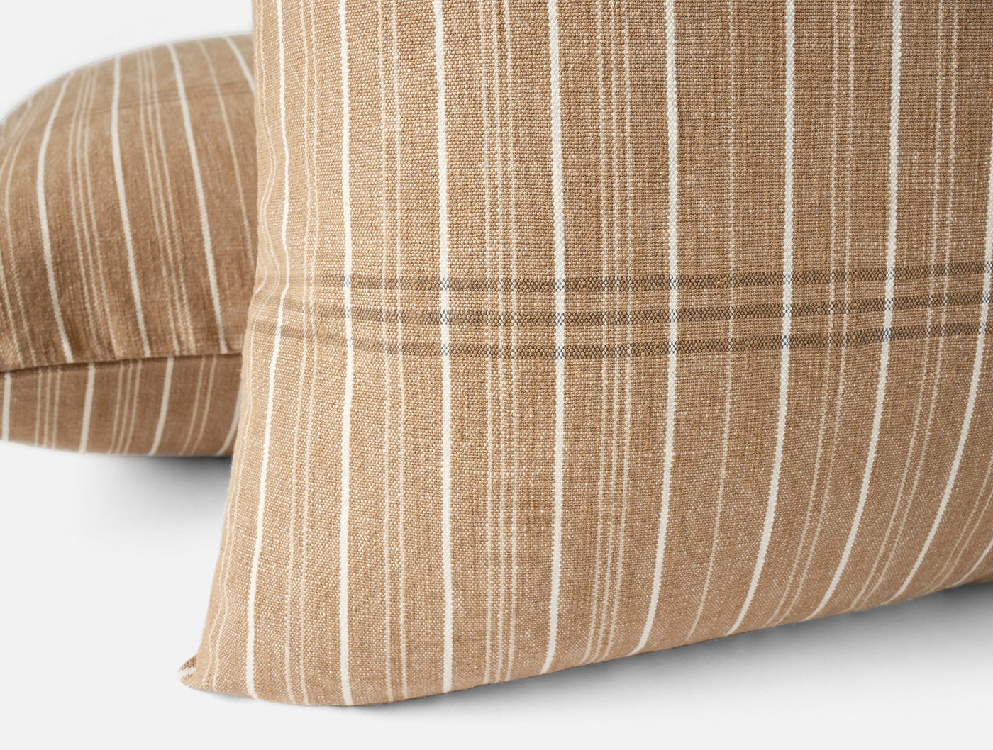 Close-up of Coyuchi Fernwood pillow covers in tan with white and brown woven stripes.