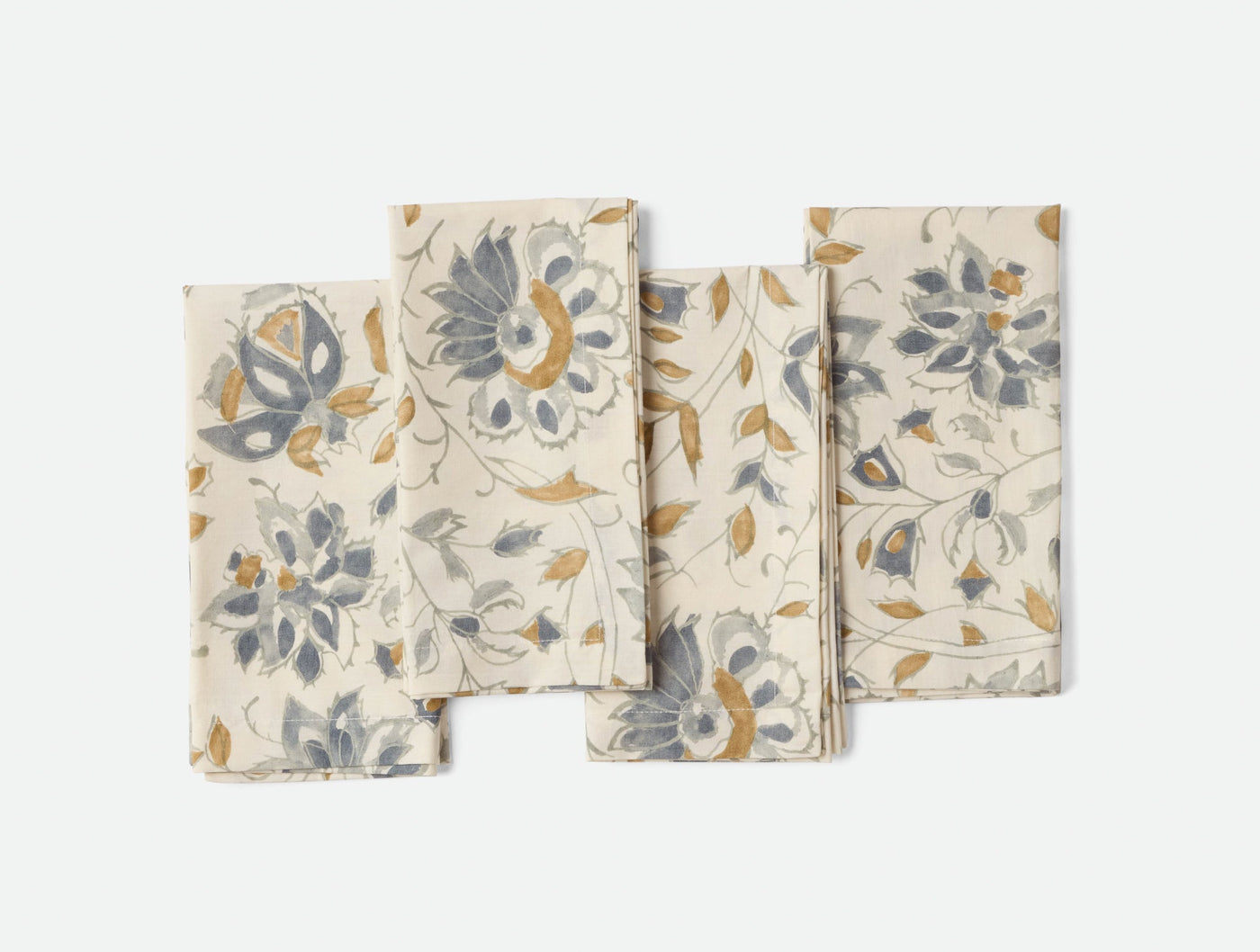 Coyuchi Flora Print napkins fanned out, ivory with slate and gold floral pattern.