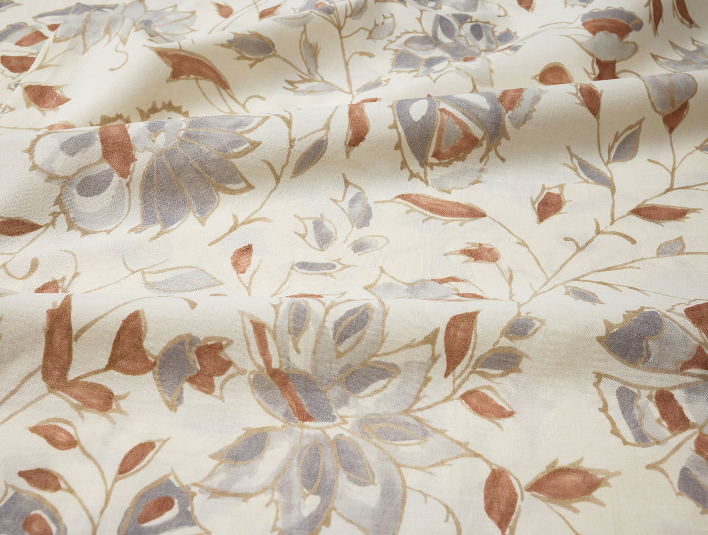 Close-up of Coyuchi Flora Print napkin fabric, ivory with dusty blue and terracotta floral print.