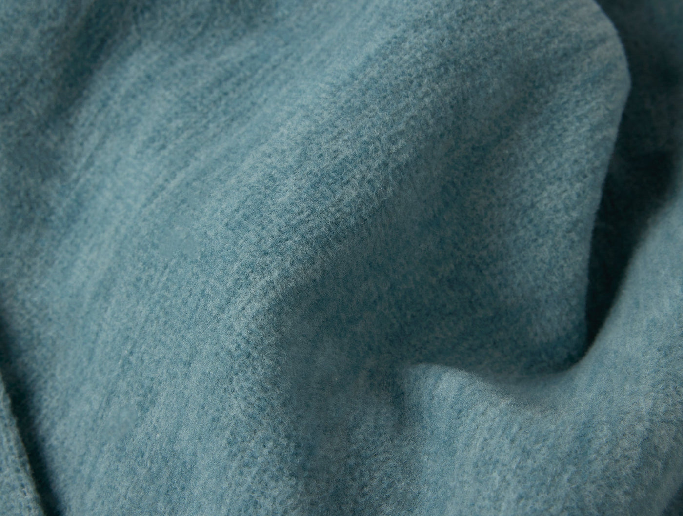 Close-up of draped teal heathered cotton throw showing soft texture and subtle weave.