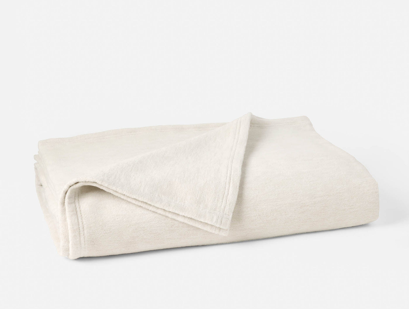 Ivory cotton blanket folded to show subtle woven texture and hem detail.