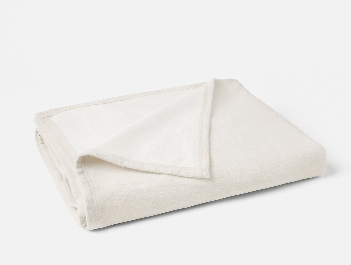 Close-up of ivory folded cotton blanket showing soft stitched border trim detail.