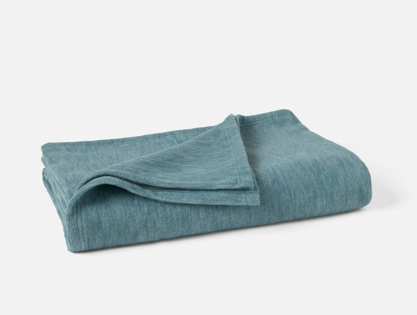 Coyuchi Full Circle Cotton Throw folded, heathered teal linen-weave texture visible.