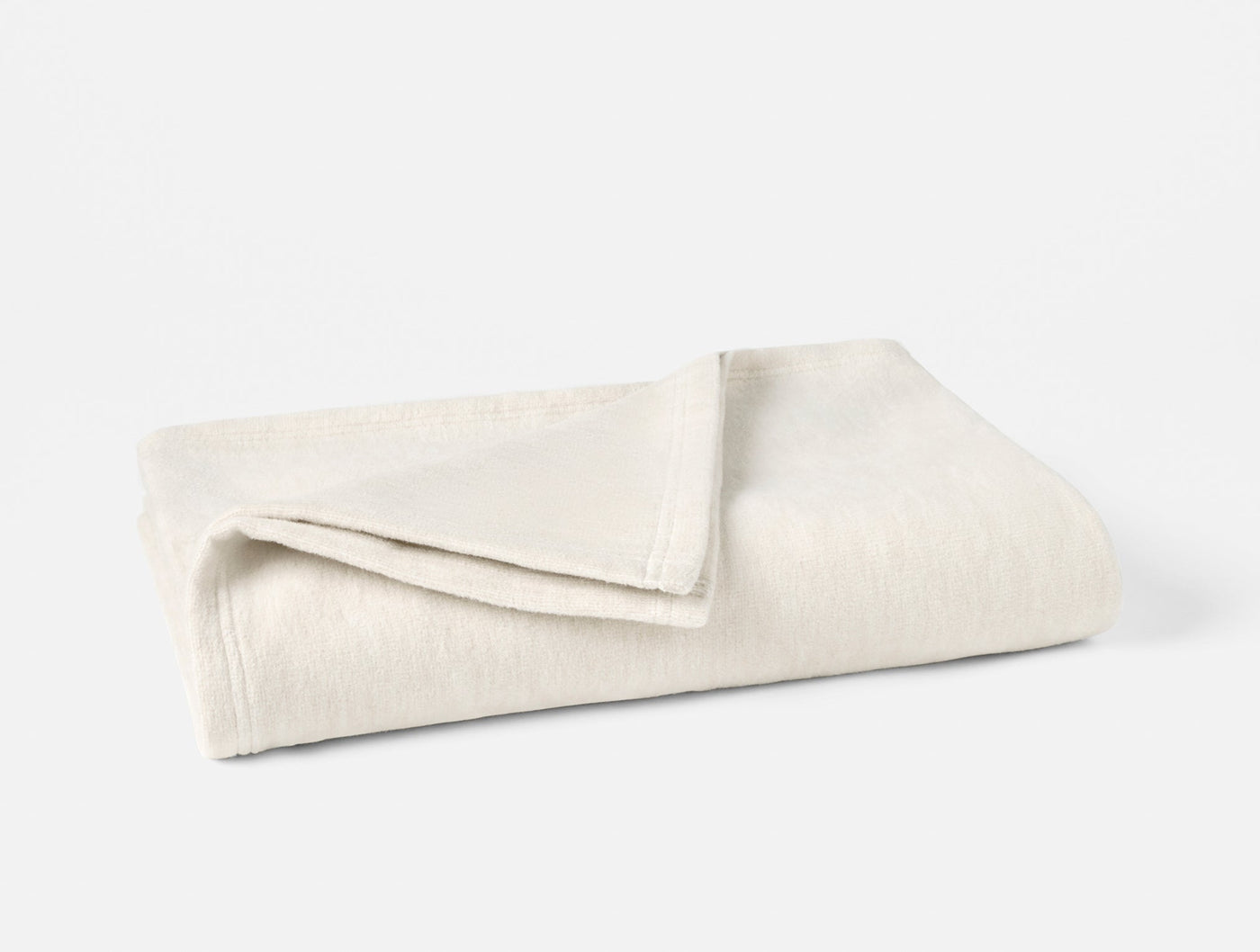 Coyuchi Full Circle Cotton Throw folded, ivory textured weave with subtle ribbed pattern.
