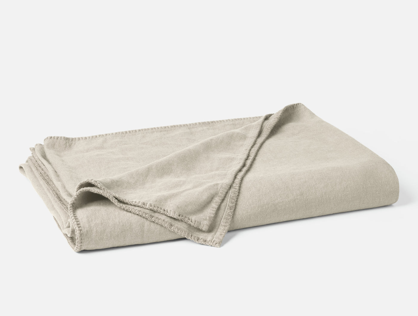 Folded oatmeal linen blanket with contrast blanket-stitch trim detail.