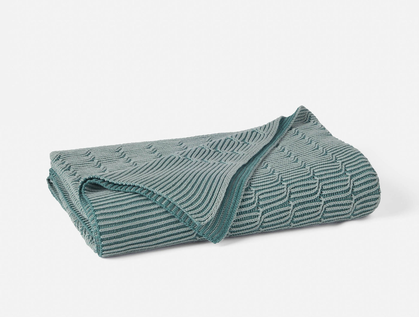 Folded Coyuchi Ivy Knit throw in teal, showing textured wave and ribbed knit pattern.