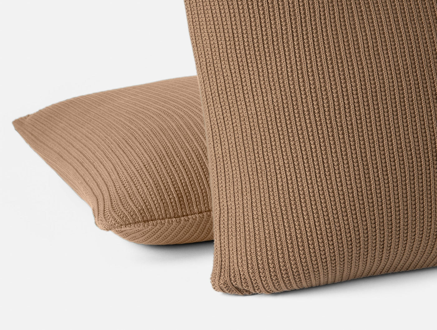 Close-up of Coyuchi Linea Knit pillow covers in camel, showing ribbed knit texture detail.