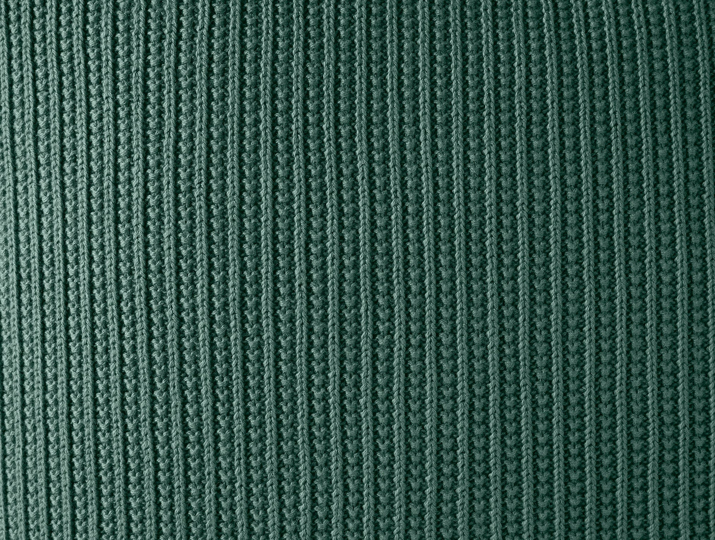 Close-up of Coyuchi Linea Knit pillow cover showing forest green ribbed knit texture.