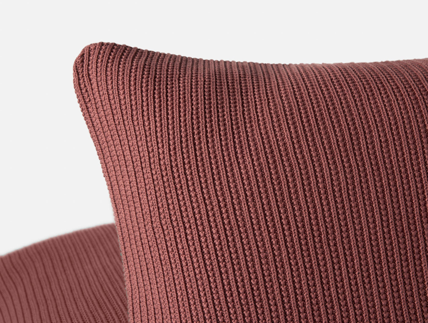 Close-up of Coyuchi Linea Knit pillow corner in terracotta, showing ribbed knit texture.