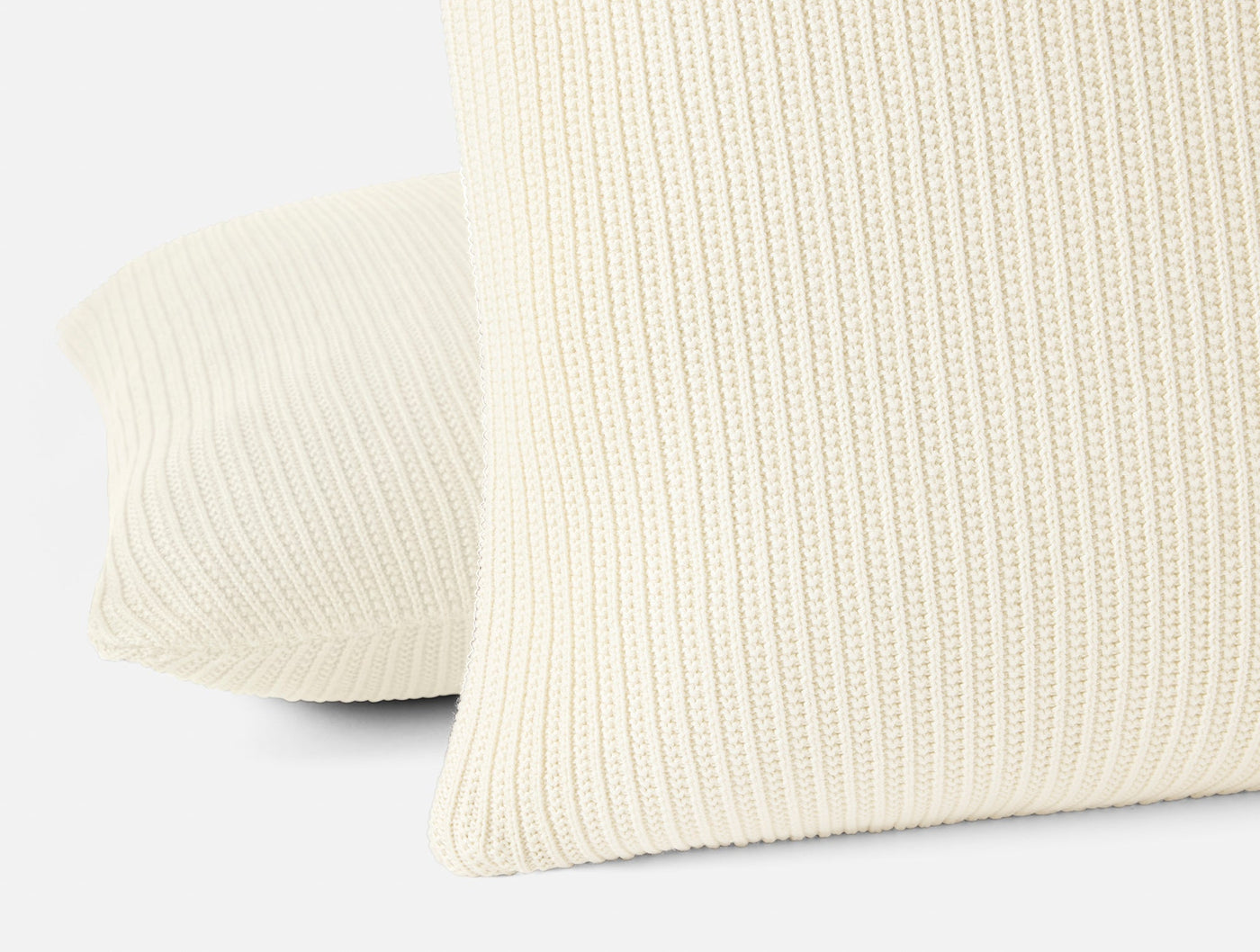 Close-up of ivory knit texture on Linea Decorative Pillow covers, showing ribbed pattern detail.