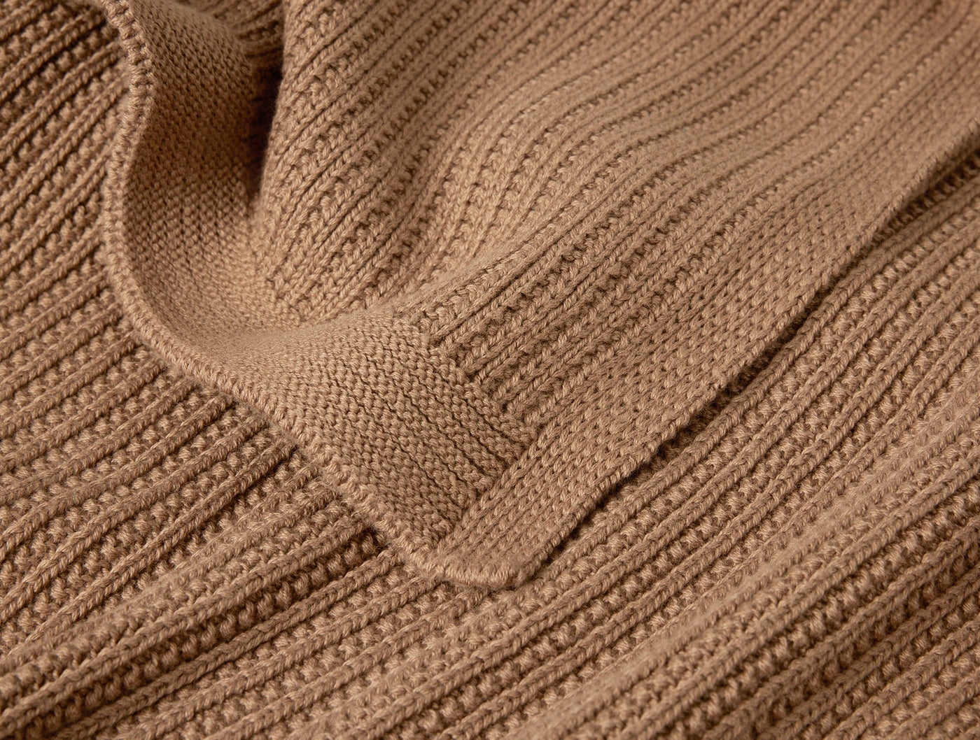 Close-up of Coyuchi Linea Knit Throw showing camel ribbed texture and folded edge detail.