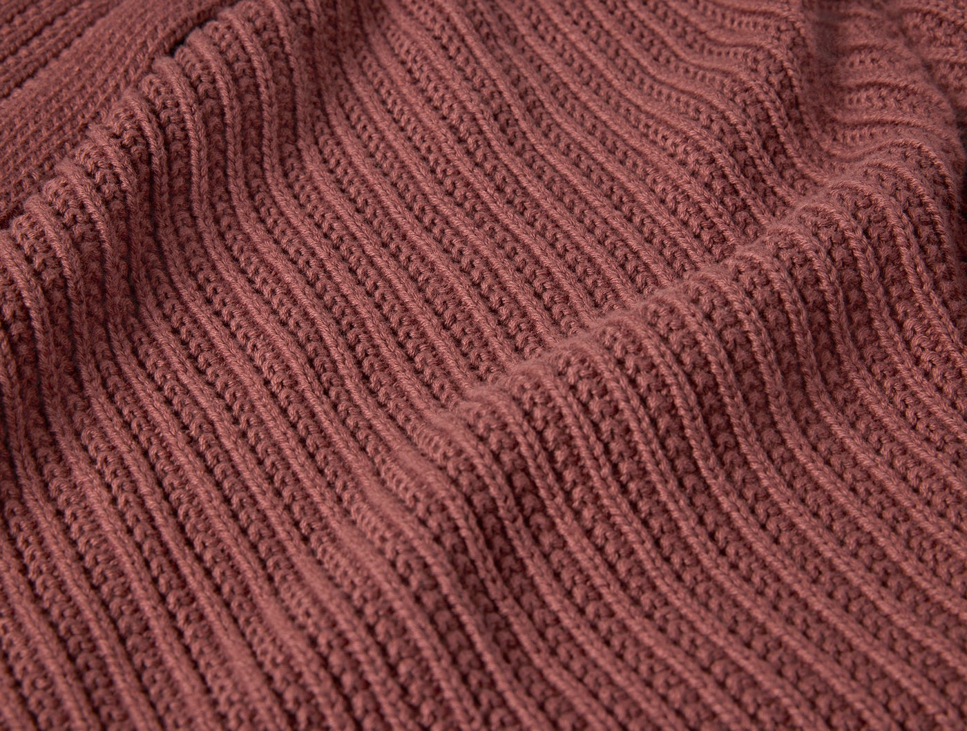 Close-up of Coyuchi Linea Knit Throw in terracotta, showing ribbed knit texture with soft draping.