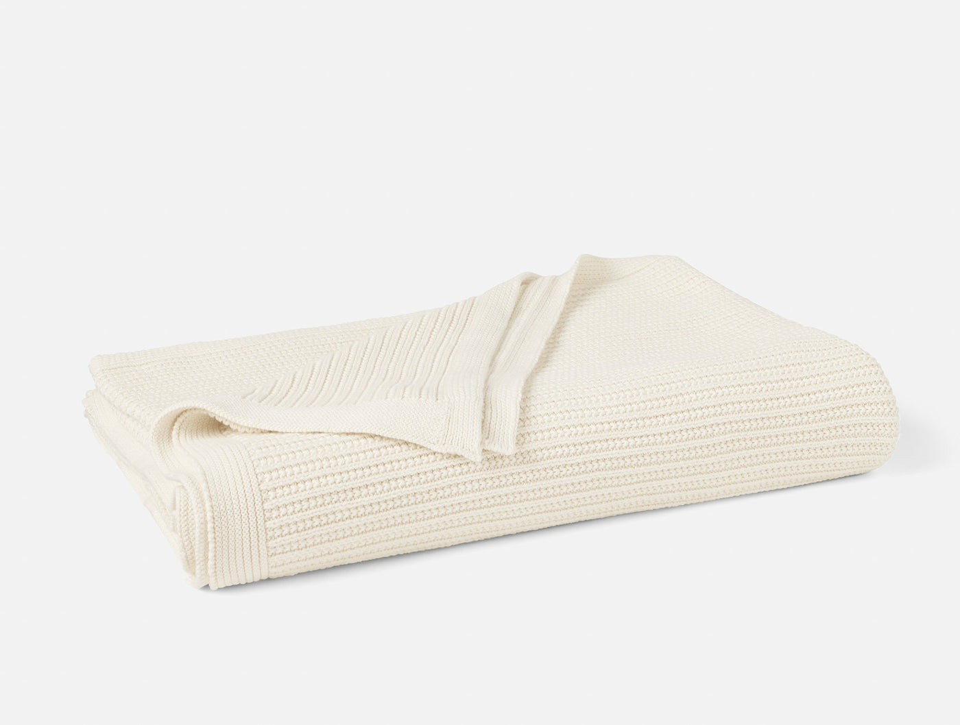 Ivory knit throw folded to show ribbed texture and natural weave detail.