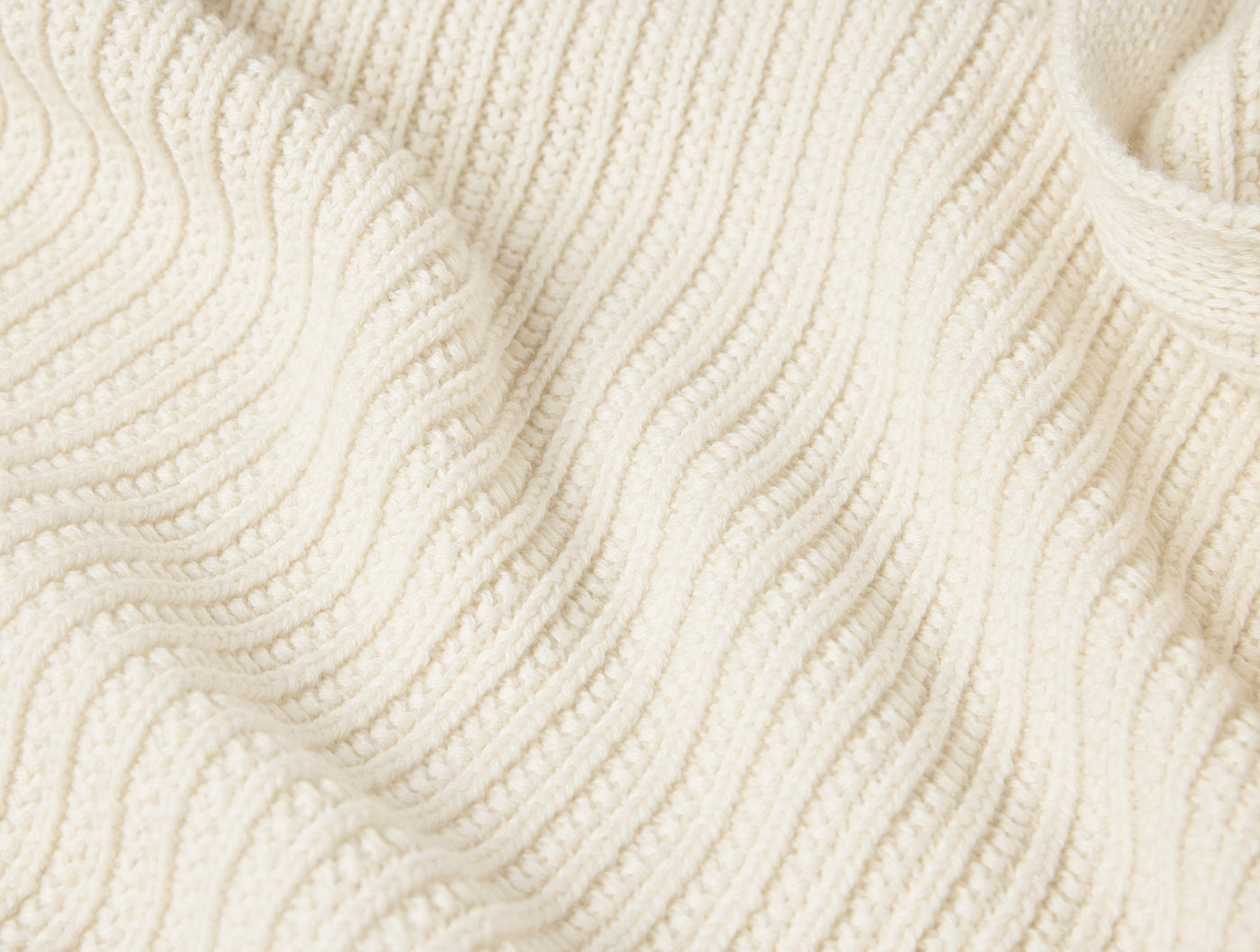 Close-up of ivory chunky ribbed knit texture on a draped Coyuchi Linea throw.