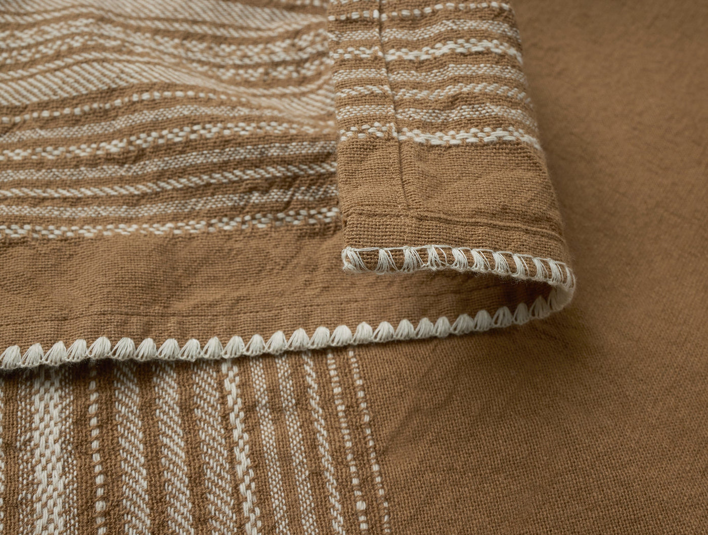Close-up of Coyuchi Oak hand towel hem with cream blanket-stitch trim and woven stripe detail.