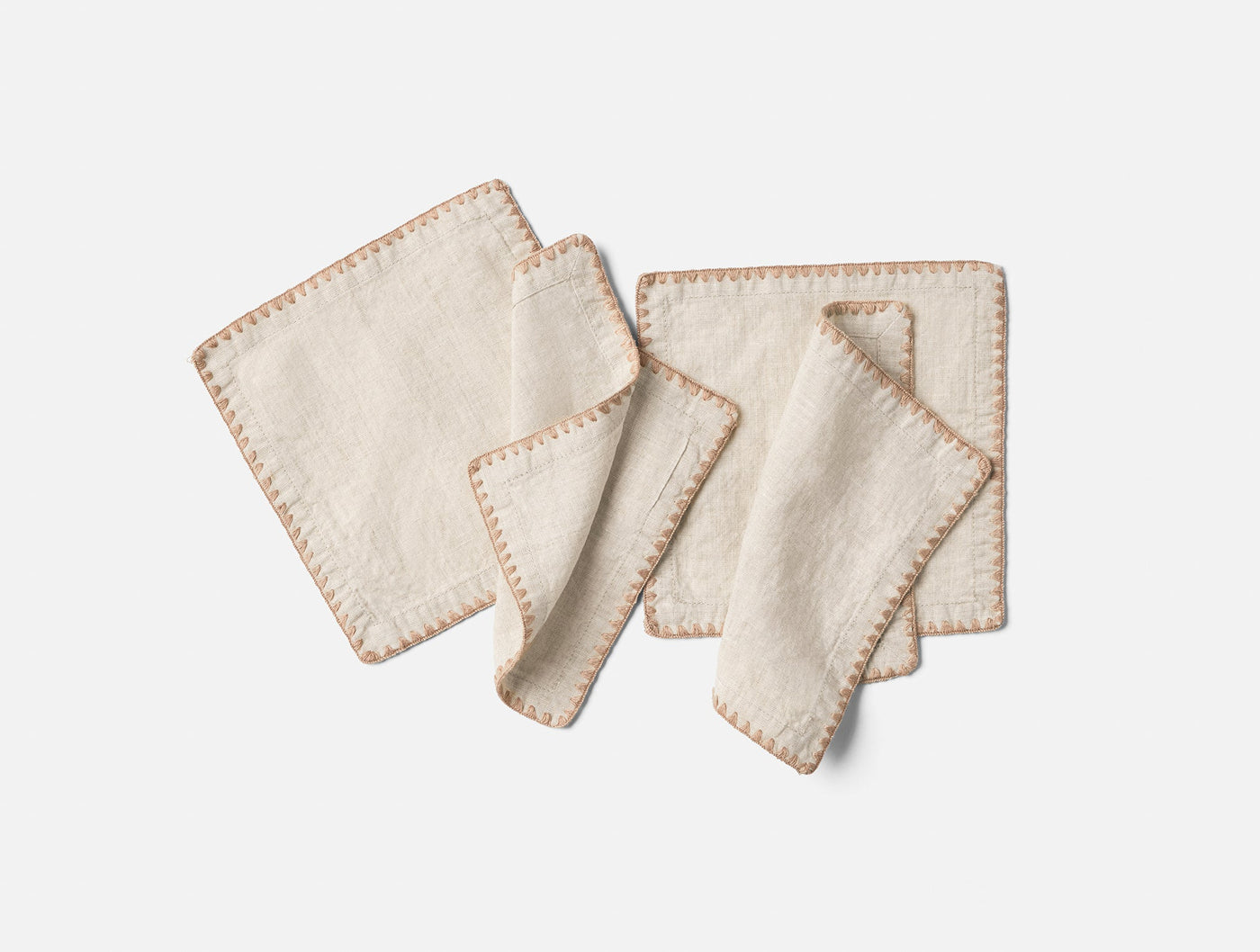 Set of four ivory linen cocktail napkins with terracotta blanket-stitch embroidered edges.