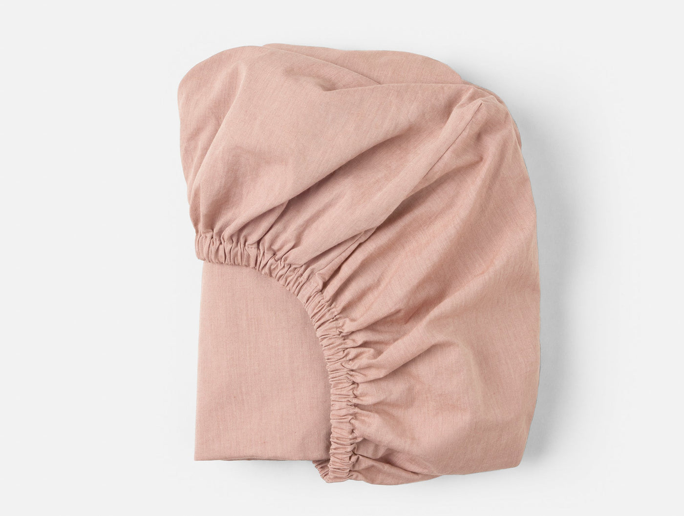 Coyuchi Crinkled Percale fitted sheet in blush, showing elasticized corner detail.