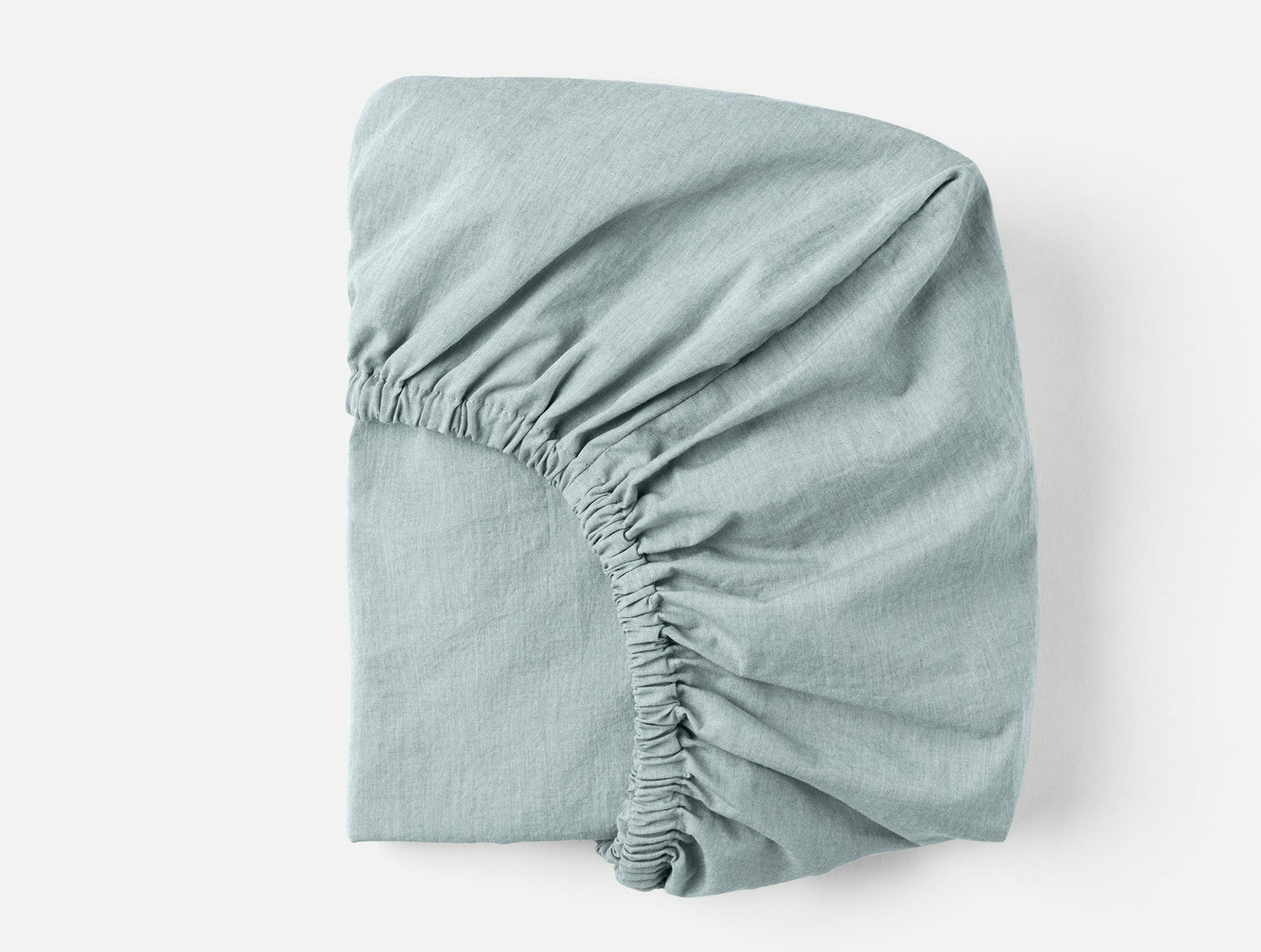 Coyuchi Crinkled Percale fitted sheet folded, seafoam, showing elasticated corner detail.