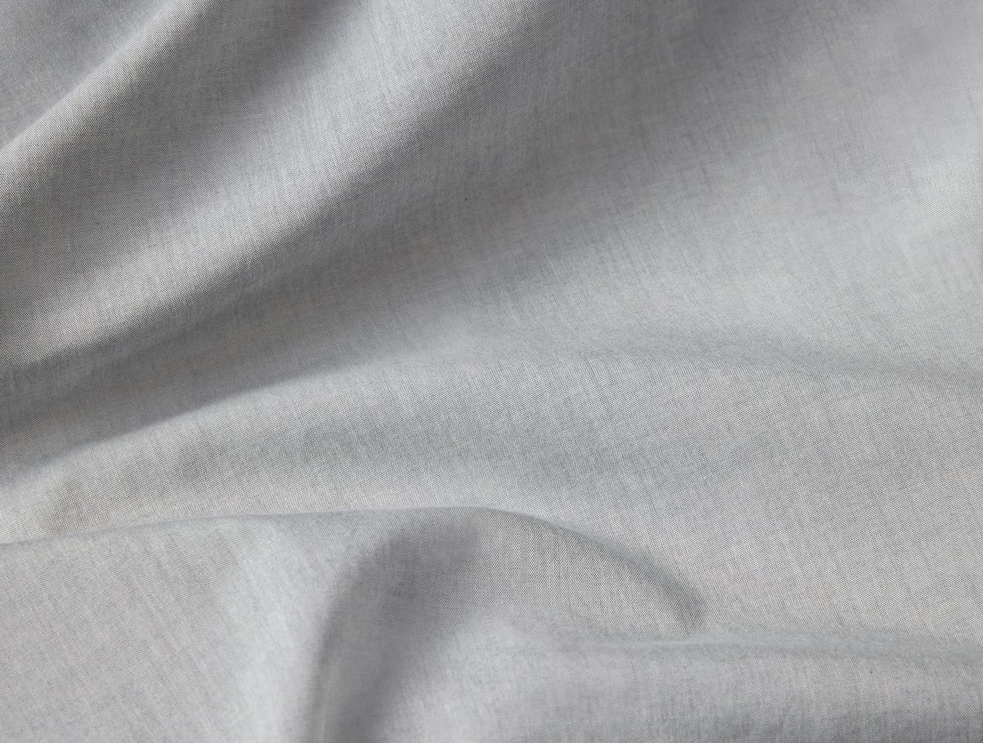 Close-up of softly draped silver grey crinkled percale fabric showing natural texture.