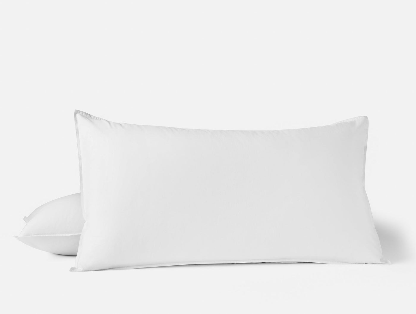 Close-up of two stacked white Coyuchi Crinkled Percale pillow shams against a light background.