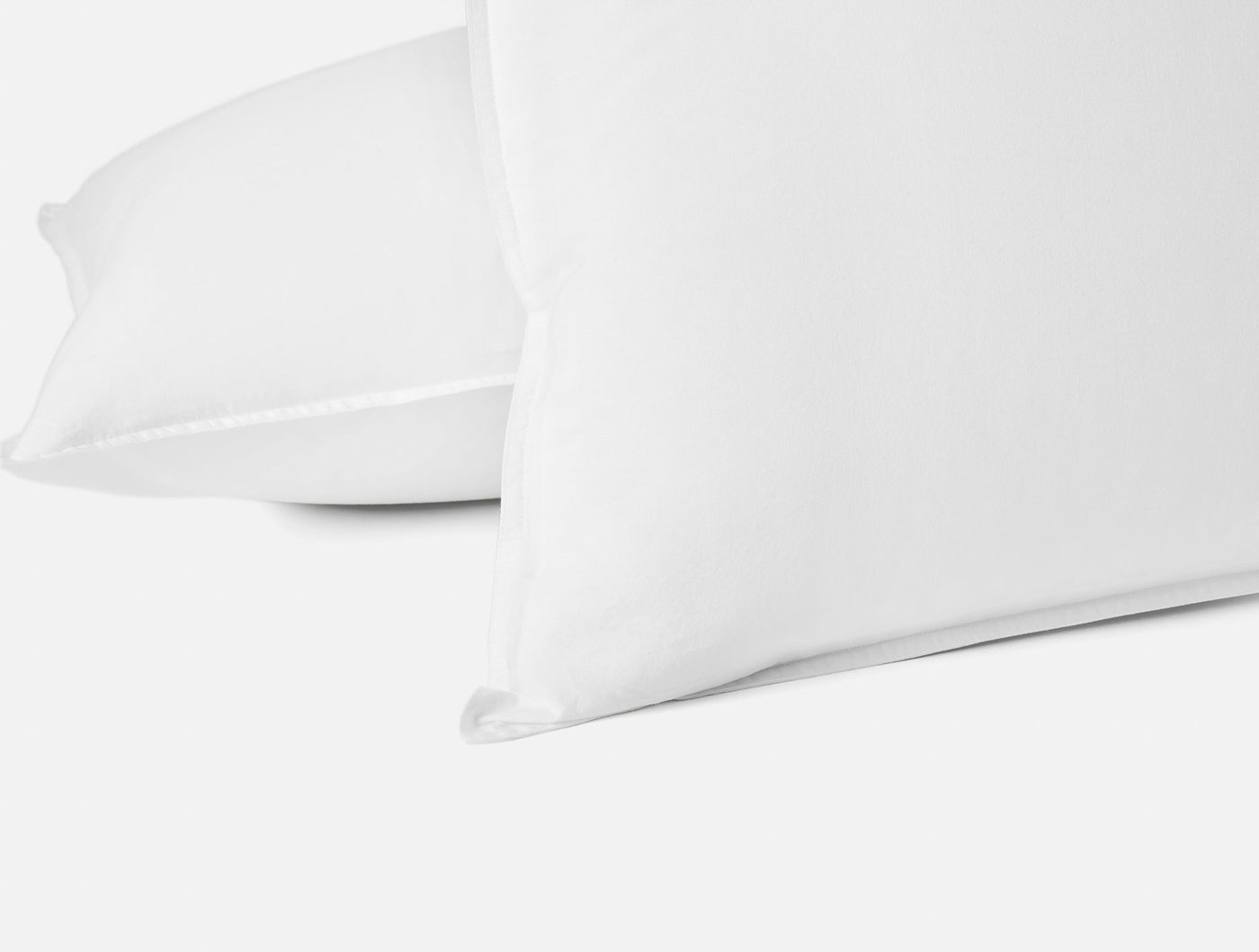 Close-up of white Coyuchi Crinkled Percale pillow sham edge, showing textured percale weave detail.