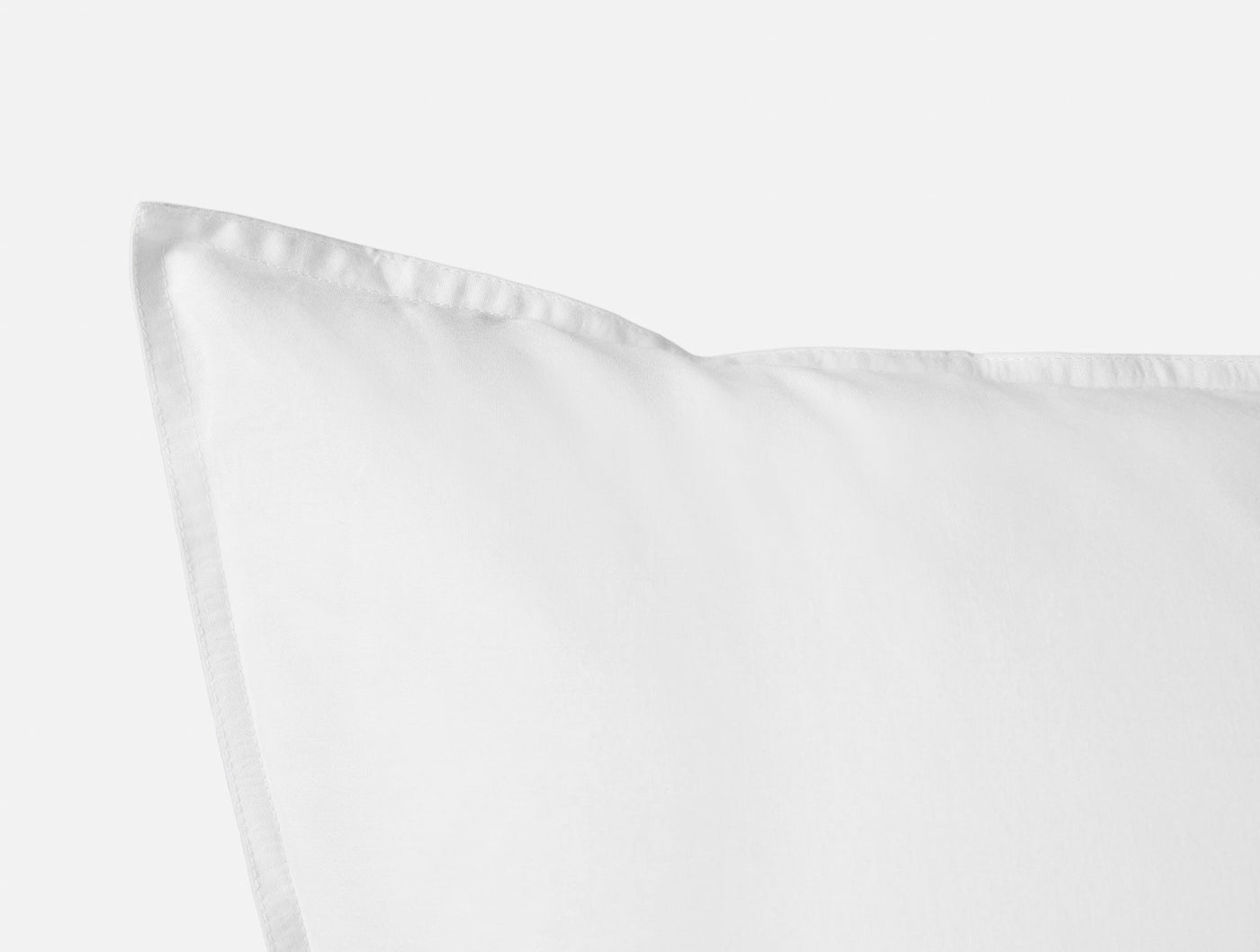 Close-up of white pillow sham corner showing crisp percale weave and stitched border detail.