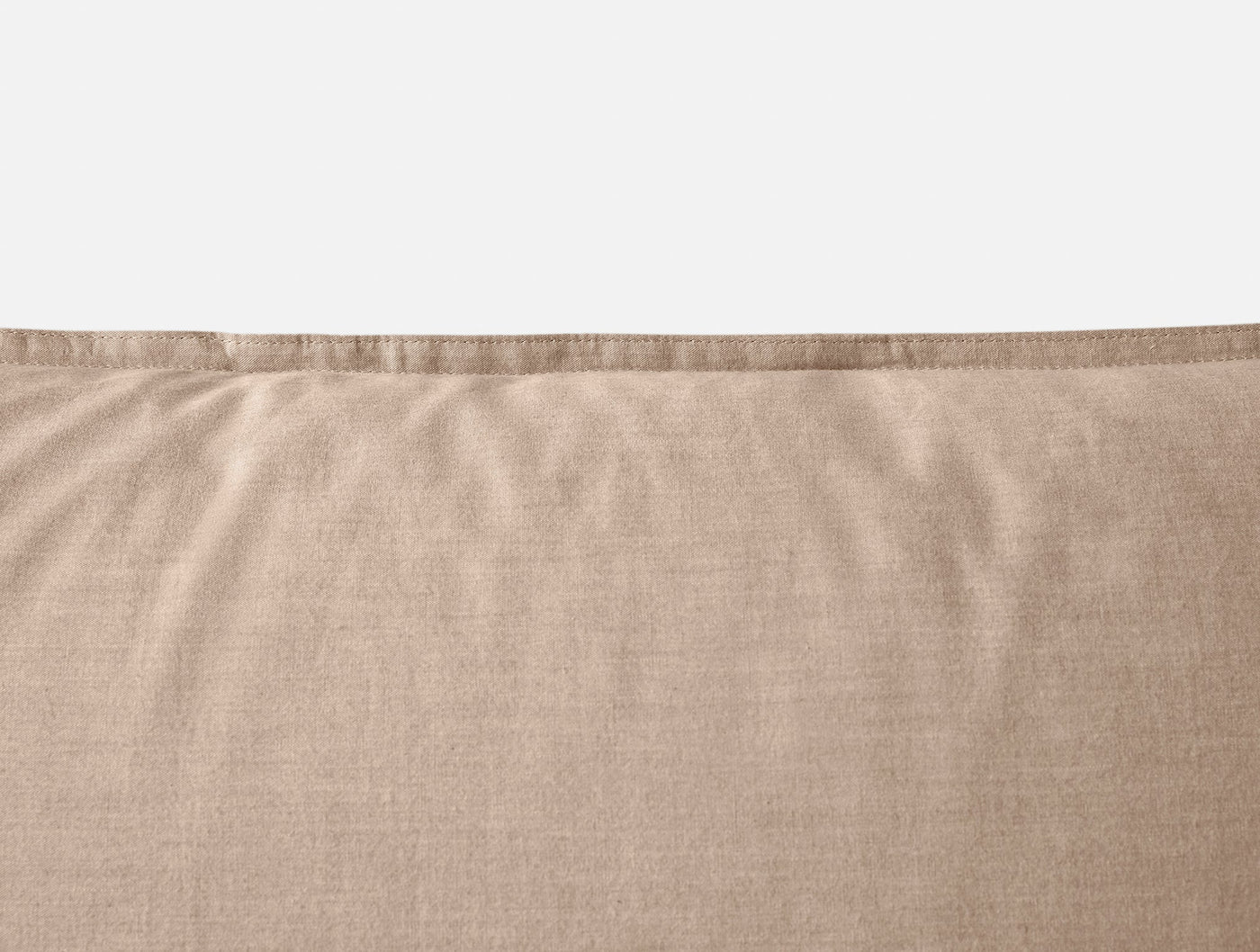 Close-up of Coyuchi Crinkled Percale sham top edge in warm sand linen-like fabric.