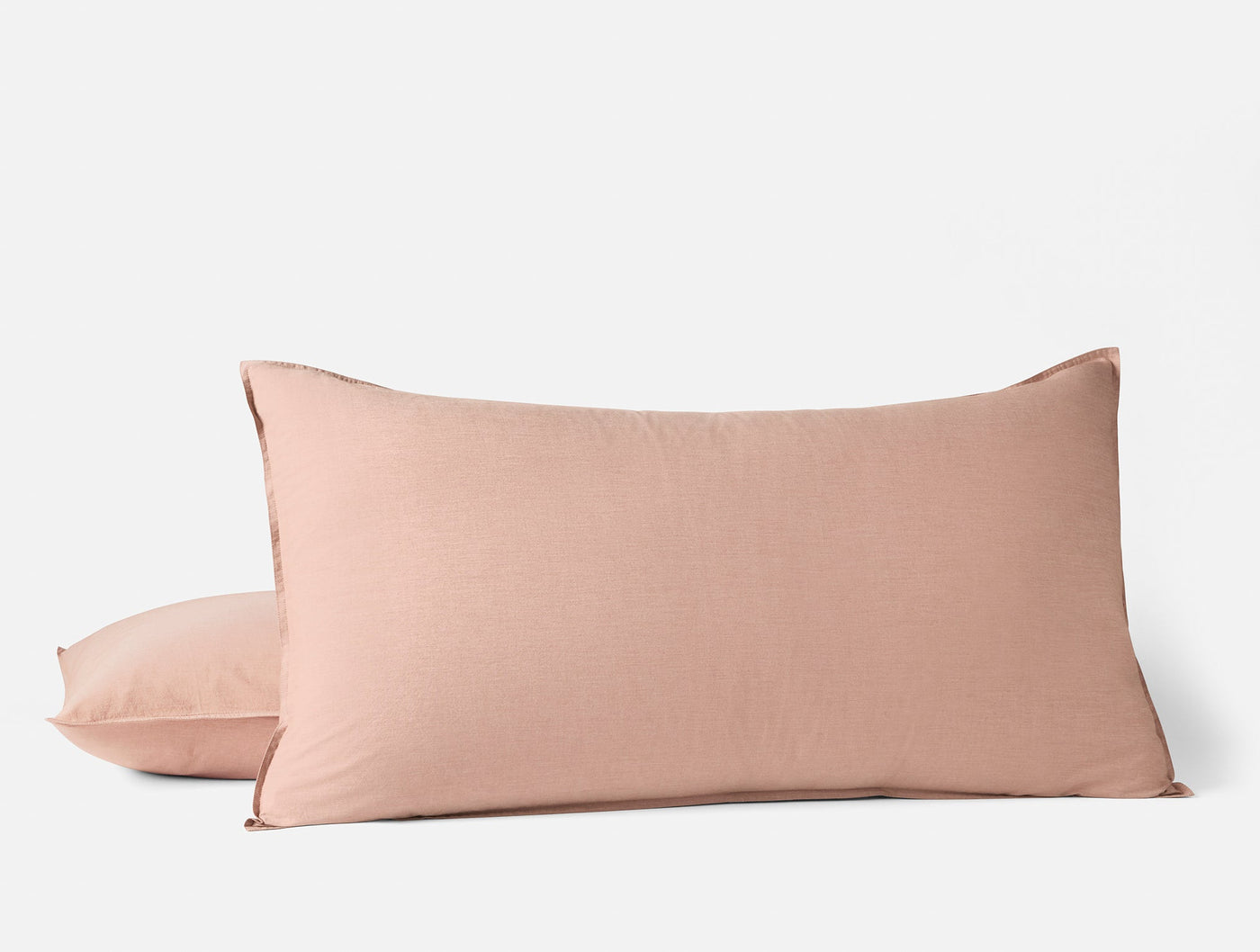 Two blush Coyuchi Crinkled Percale pillow shams stacked, showing textured cotton surface.