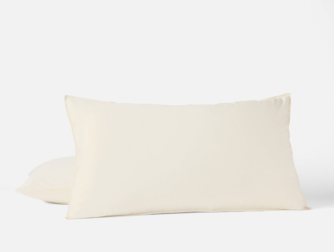 Two ivory Coyuchi Crinkled Percale pillow shams stacked, soft texture visible.