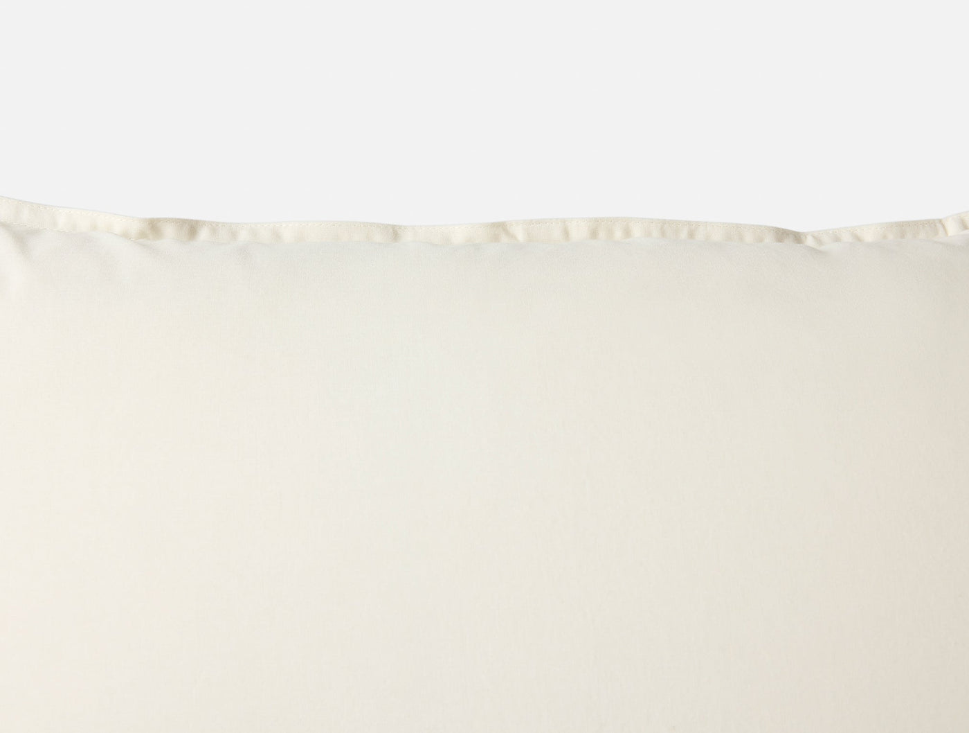 Close-up of ivory Coyuchi Crinkled Percale sham top edge with delicate ruffle trim detail.