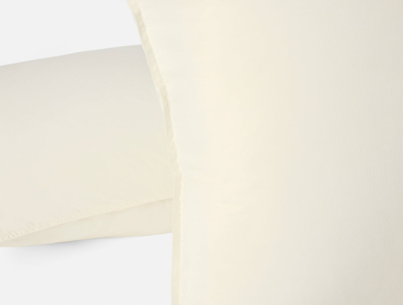 Close-up of ivory Coyuchi Crinkled Percale pillow sham edge showing hem detail.
