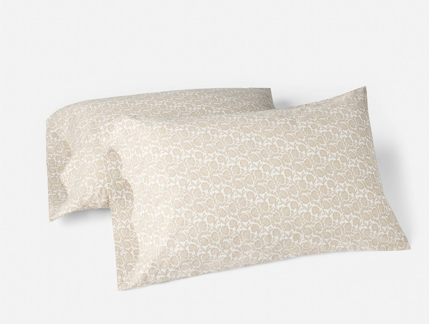 Pair of Coyuchi percale pillowcases in sand with tonal floral geo print, stacked at an angle.