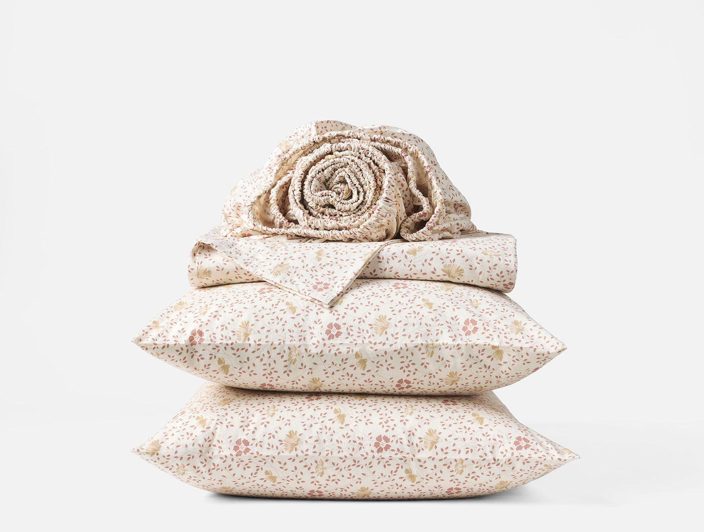 Close-up of stacked Coyuchi Print Percale sheet set in ivory with delicate floral print.