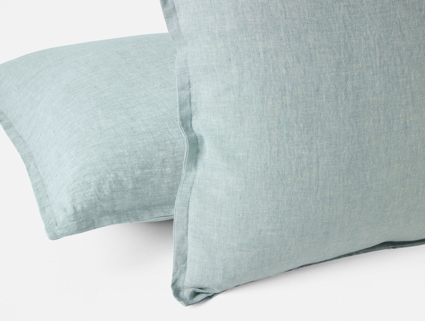 Close-up of Coyuchi Relaxed Linen pillow covers in muted aqua, showing woven texture and flange edge.