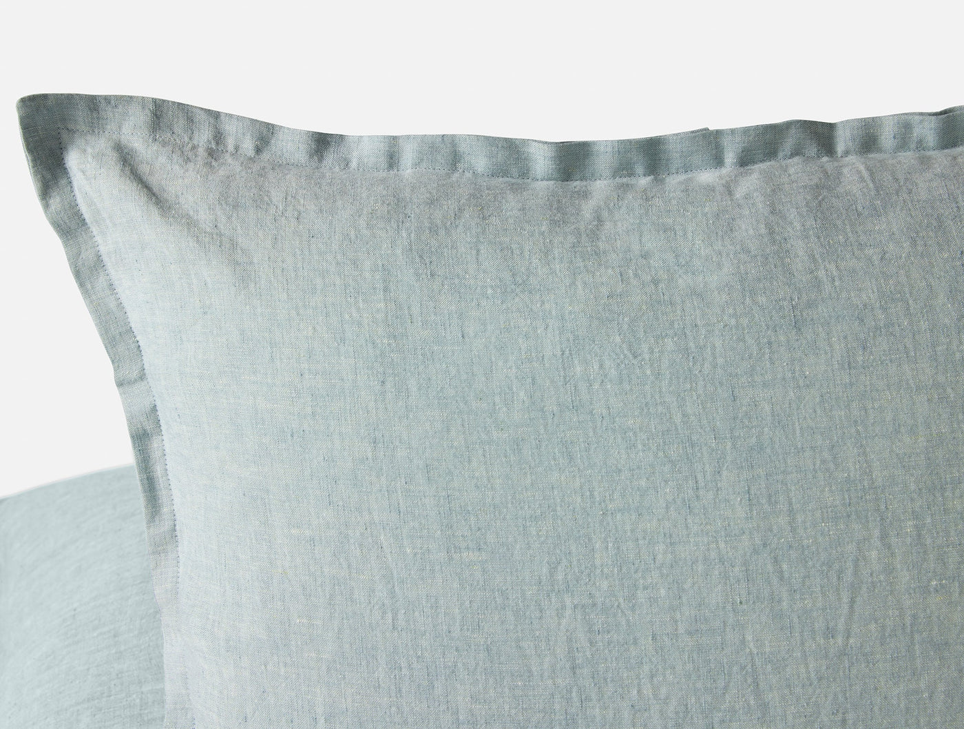Close-up of sage green washed linen pillow cover corner showing flange edge detail.