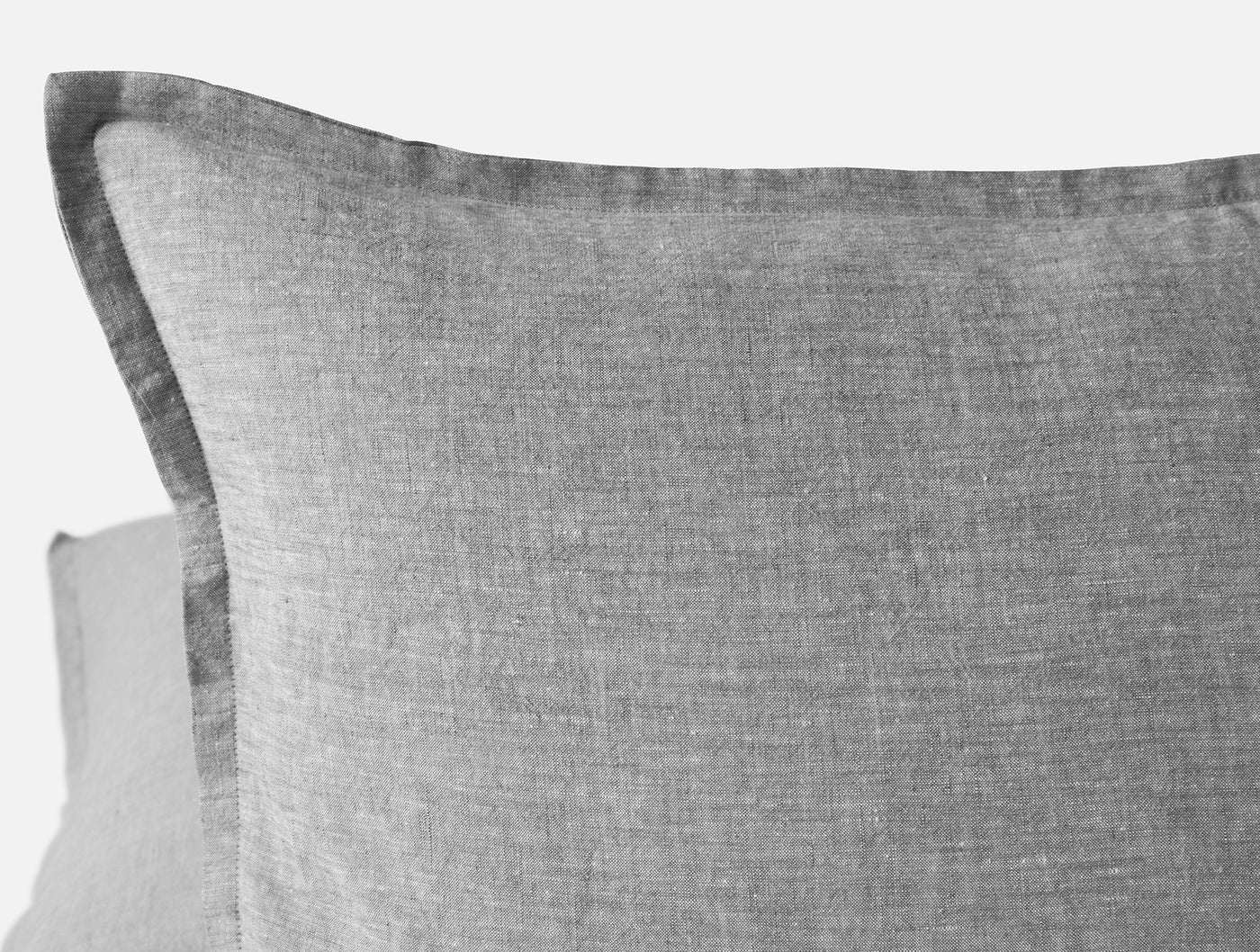 Close-up of Coyuchi Relaxed Linen pillow corner, showing flanged edge and woven grey texture.
