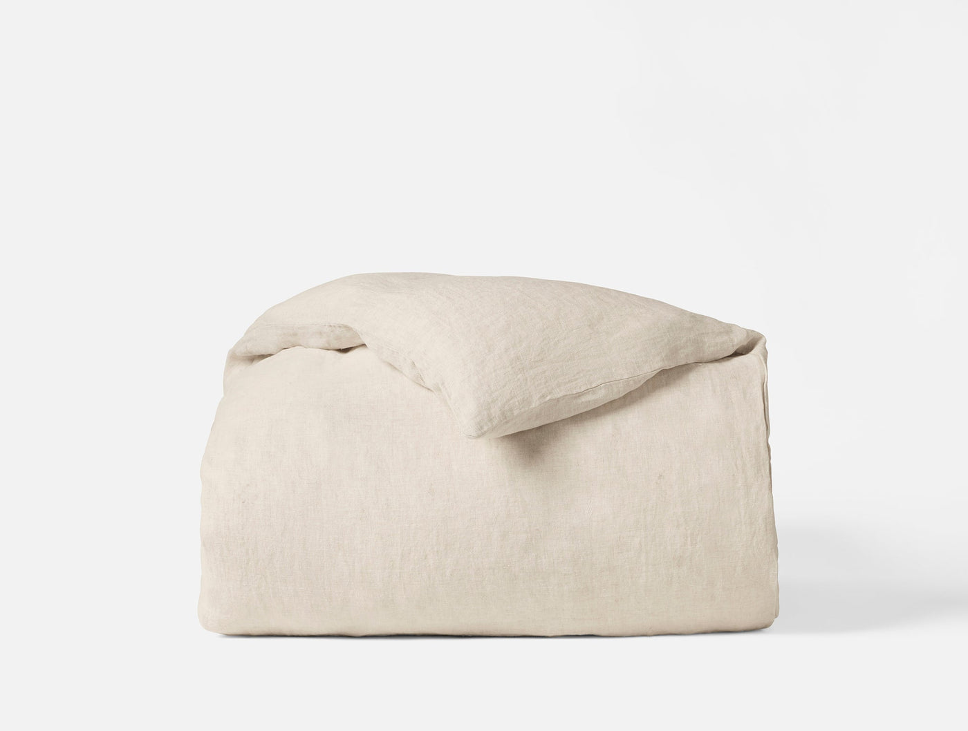 Coyuchi Relaxed Linen duvet cover in natural, folded with pillow on white background.