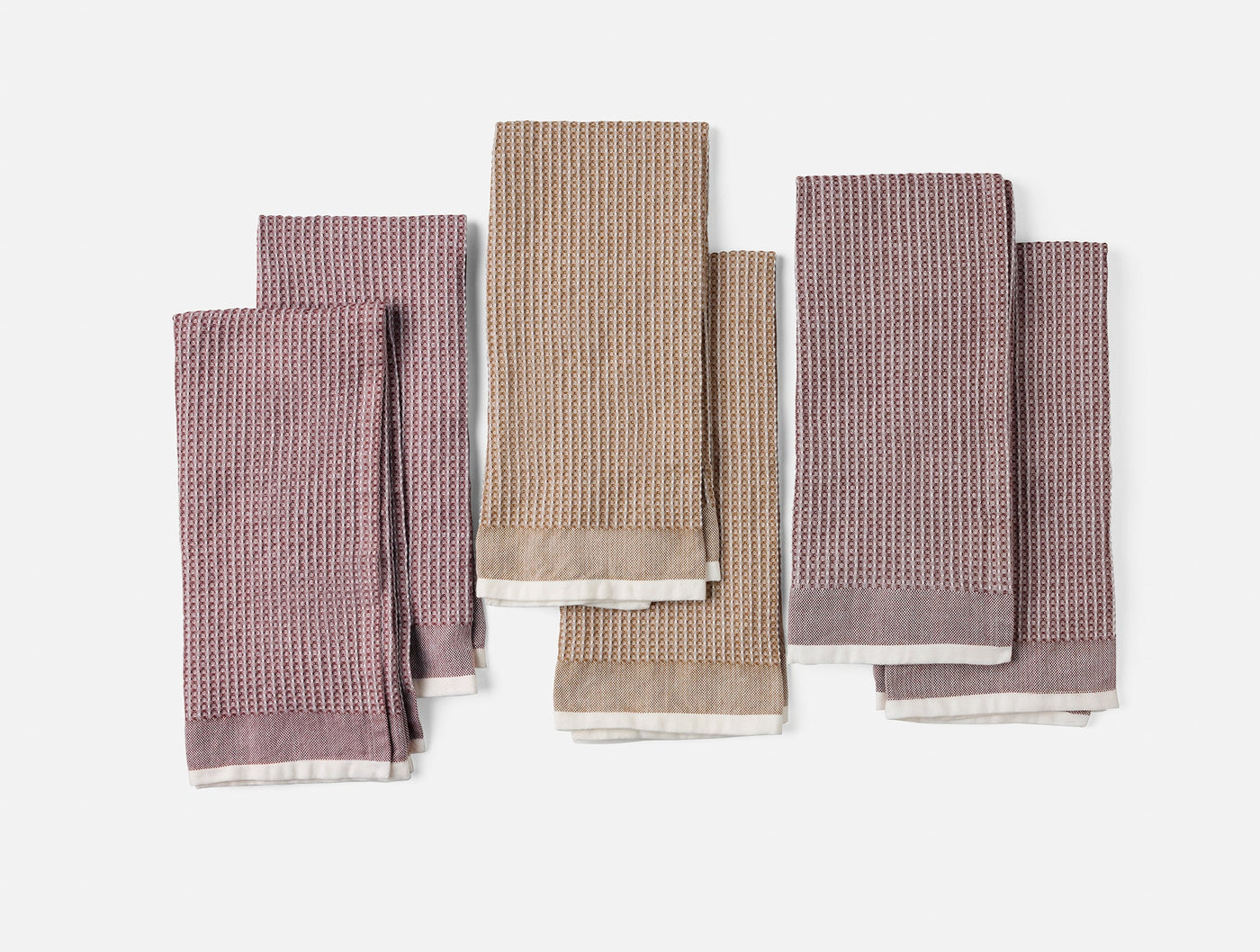 Coyuchi Waffle Kitchen Towel Set in mauve, taupe, and charcoal waffle-weave linen, flat lay.