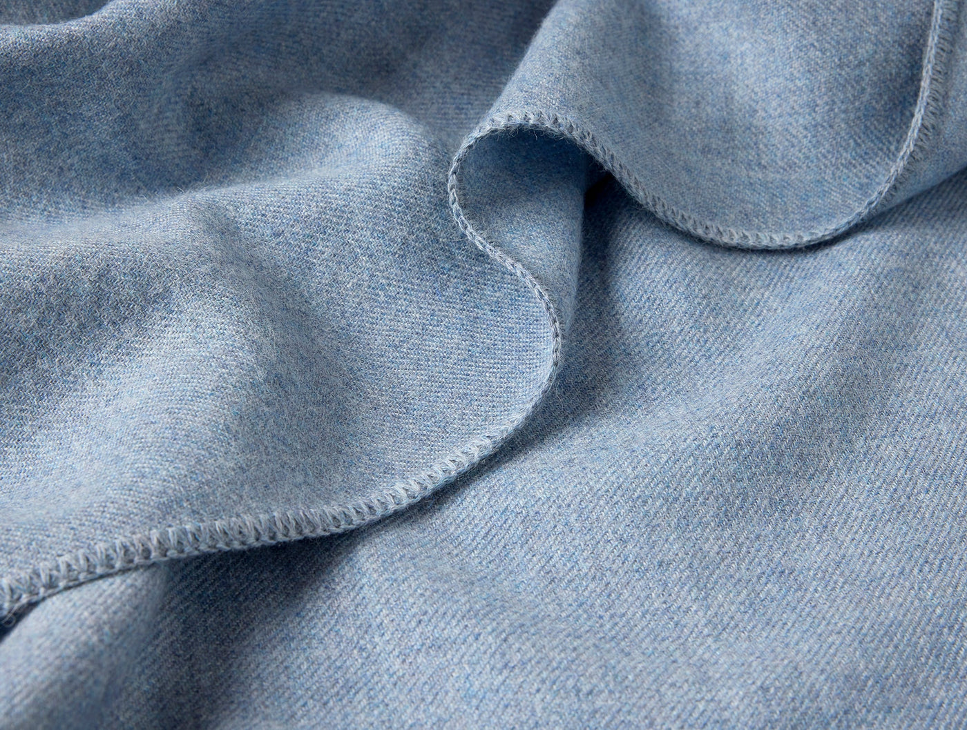 Close-up of sky blue baby alpaca blanket hem with blanket-stitch edge detail.
