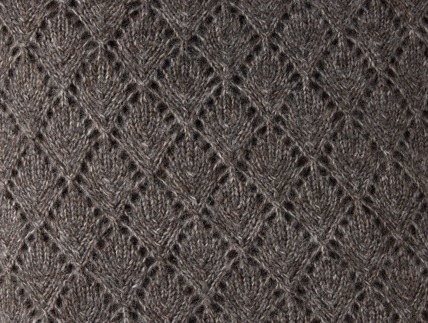 Close-up of Coyuchi Paracas pillow cover showing charcoal lace-knit alpaca diamond and leaf pattern.