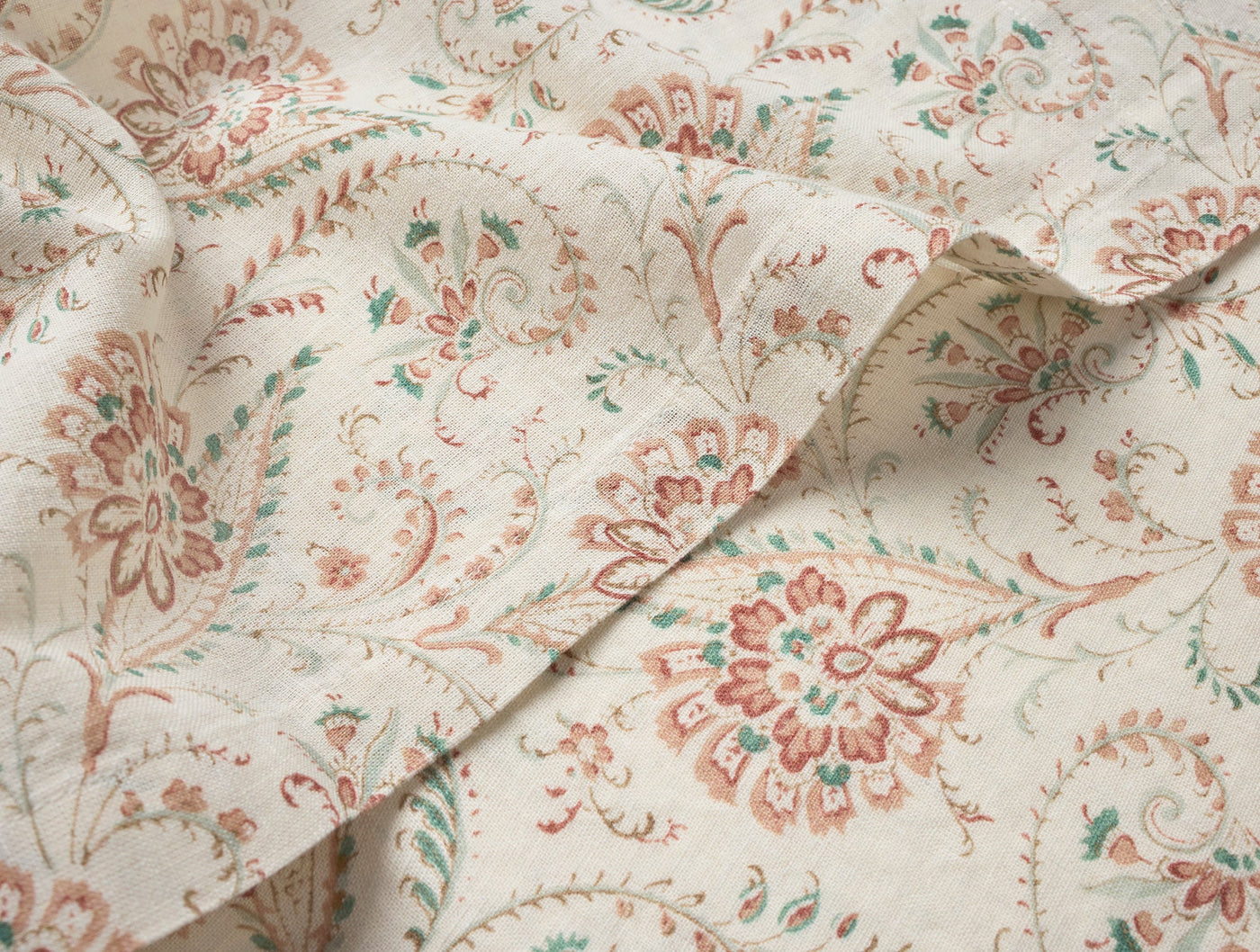 Close-up of Coyuchi Ponderosa Print napkin fabric with terracotta and sage floral medallion pattern.
