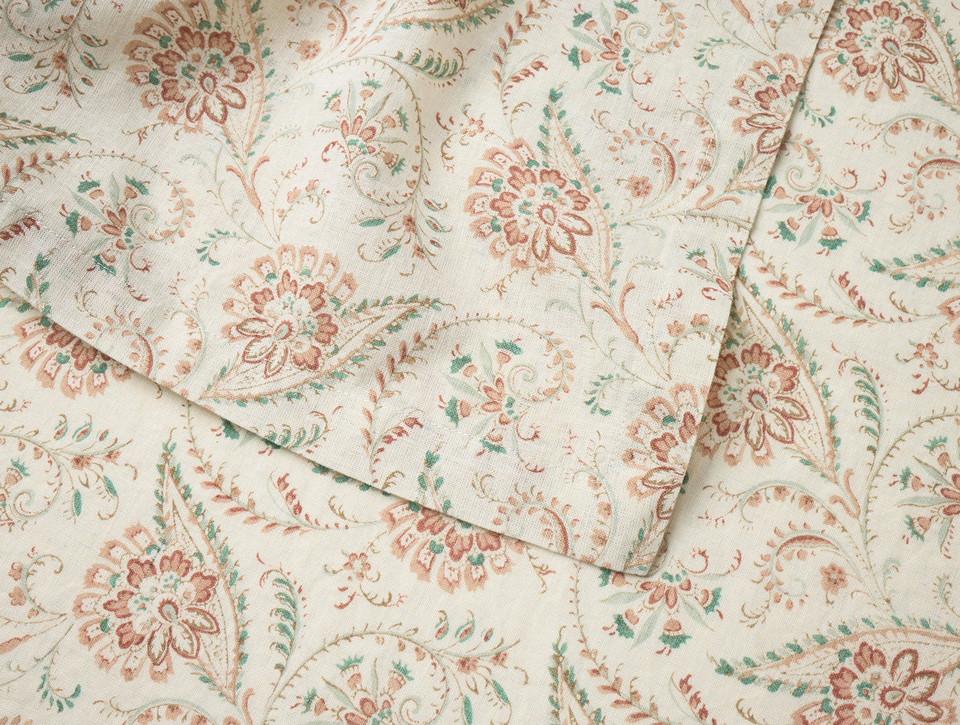 Close-up of Coyuchi Ponderosa Print runner showing terracotta and sage floral paisley pattern on ivory linen.