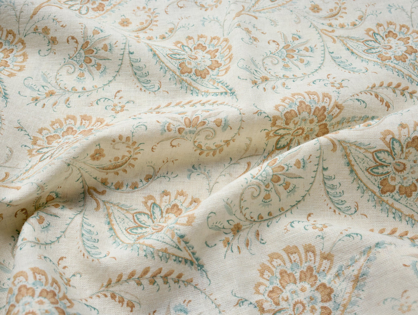 Close-up of Coyuchi Ponderosa Print tablecloth fabric with paisley motifs in amber and sage.