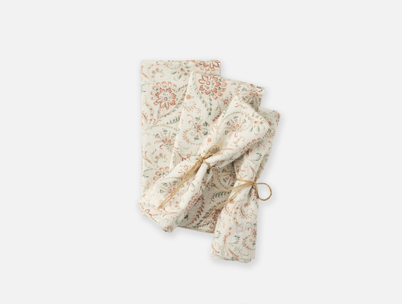 Close-up of folded Coyuchi Ponderosa Print napkins with botanical floral pattern, tied with twine.