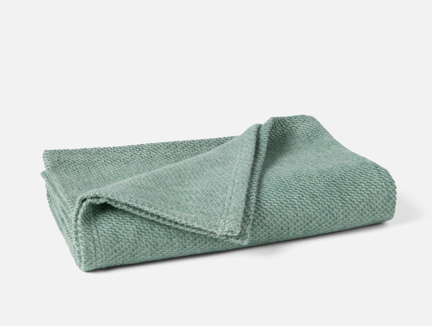 Coyuchi Sequoia throw folded, showing sage green textured weave detail.