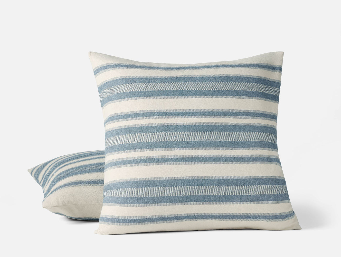 Close-up of two Coyuchi Serrano pillow covers with blue and ivory horizontal stripes.