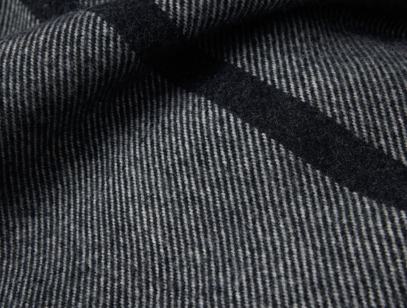 Close-up of Coyuchi Tahoe Wool throw showing charcoal herringbone weave with dark border stripe.