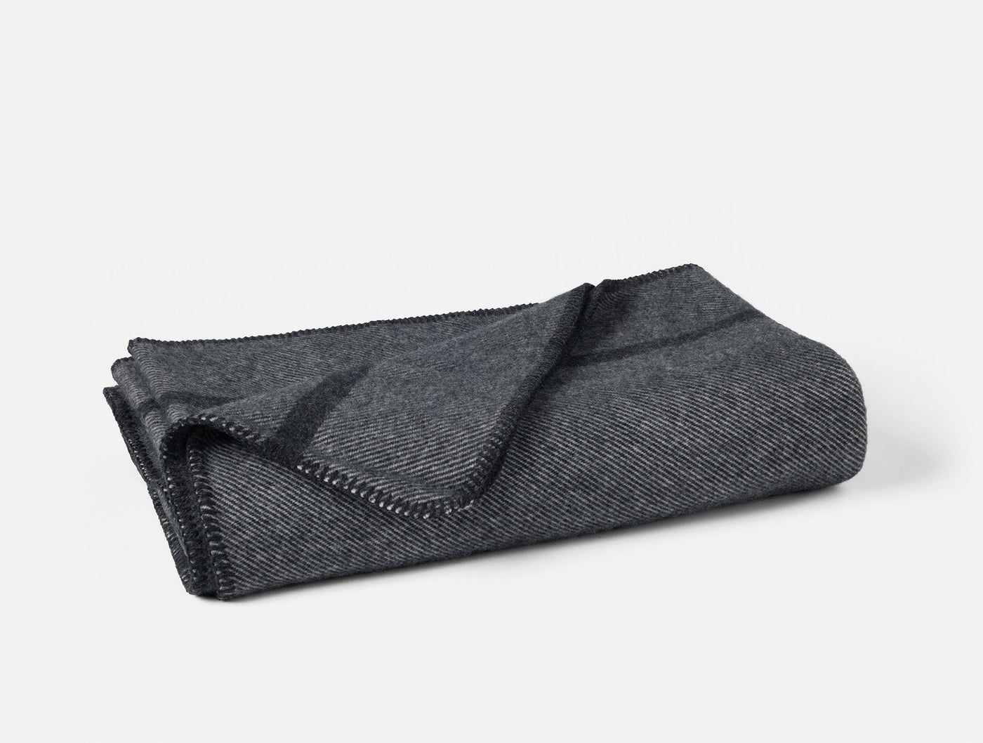 Close-up of folded Coyuchi Tahoe Wool throw in charcoal herringbone with blanket-stitch edge trim.
