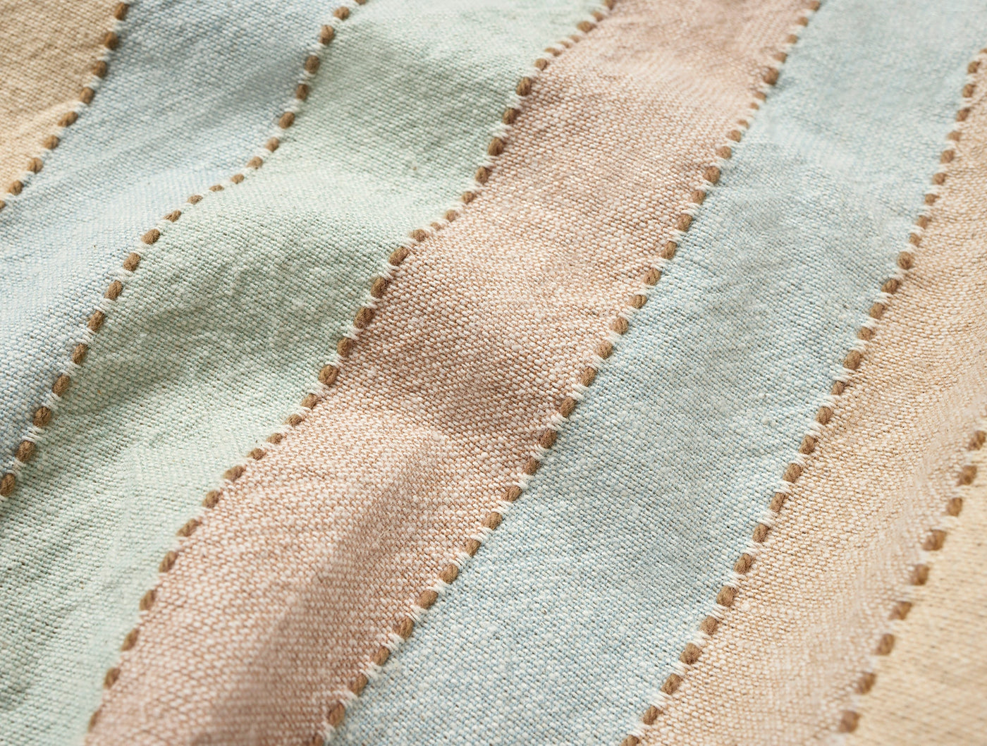 Close-up of Coyuchi Tilden napkin stitched stripe detail in sage, blush, and champagne linen.