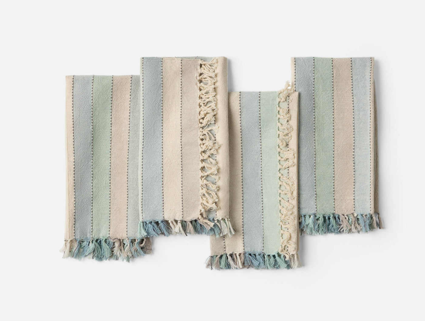 Four Coyuchi Tilden napkins flat-lay showing fringe edges and blue-green stripe weave detail.